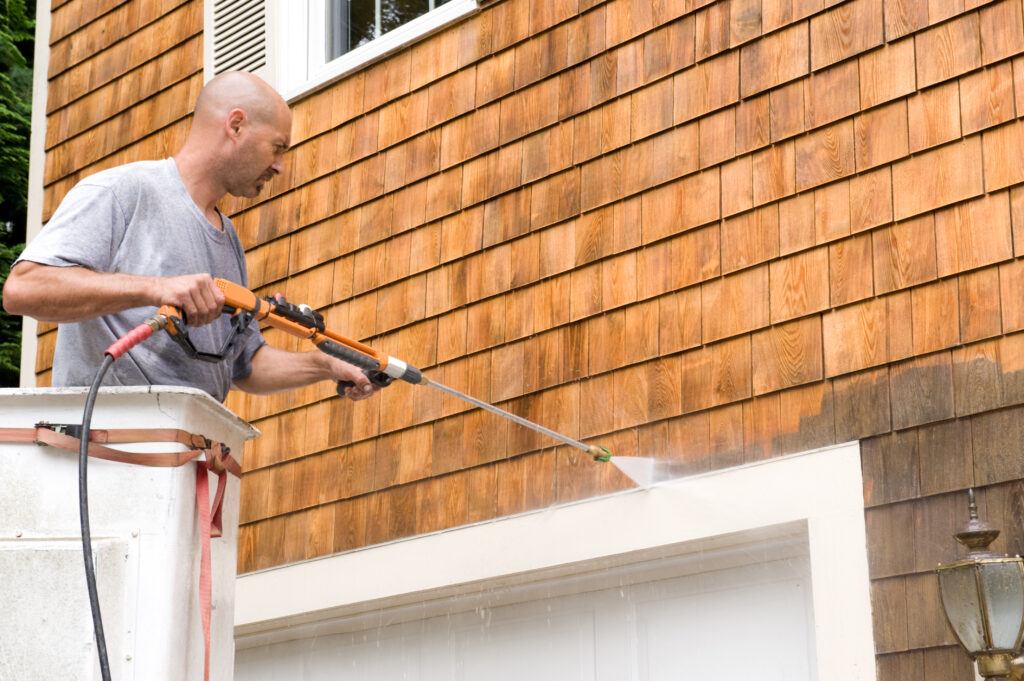 close up of man power washing exterior shingles Man in a bucket truck power washing exterior shingles.